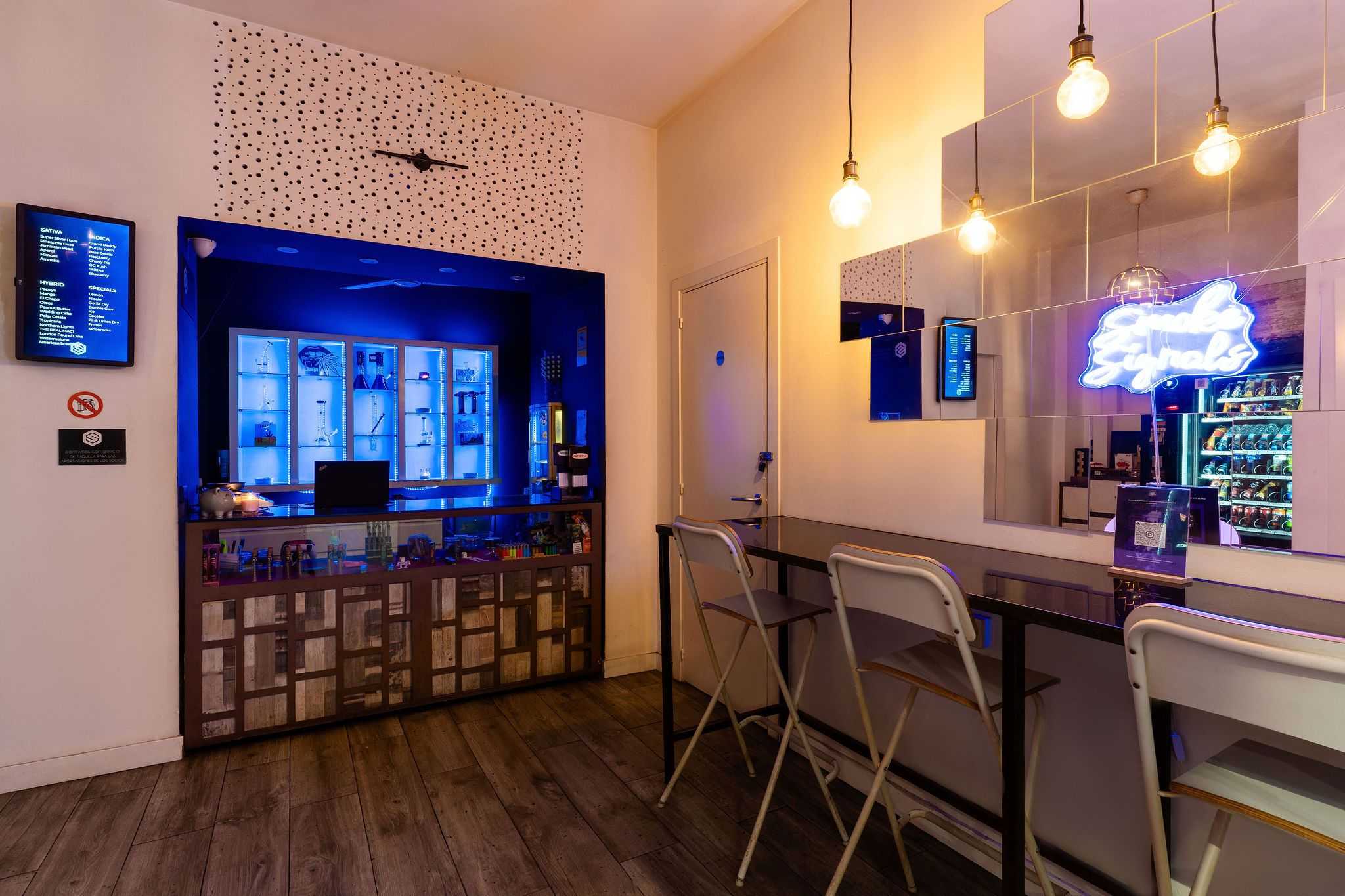 Bright bar area with illuminated display and high seating in the Barcelona Smoke Signals social club