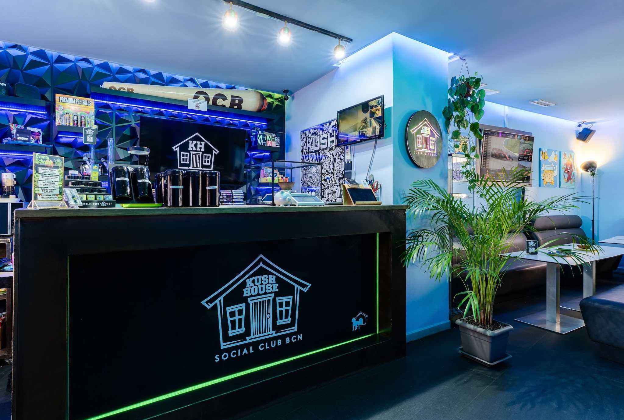 Counter with Kush House logo, illuminated decor and seating in the Barcelona cannabis club