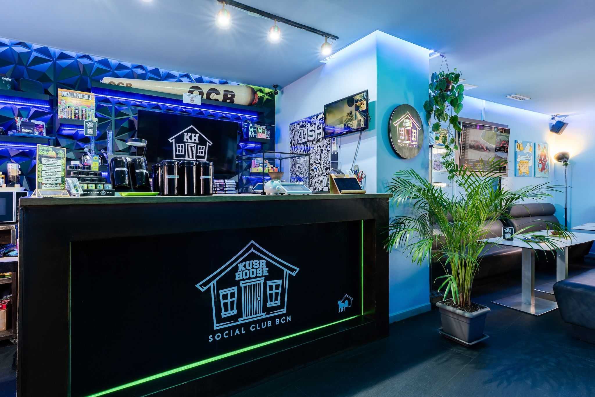 Counter with Kush House logo, illuminated decor and seating in the Barcelona cannabis club